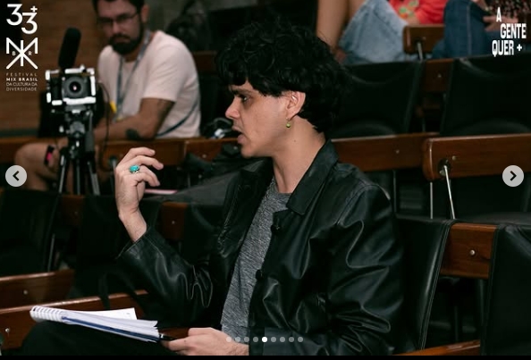 Izaque Blanco, colunista da Pista com jaqueta de couro fazendo pergunta no debate do mixlab